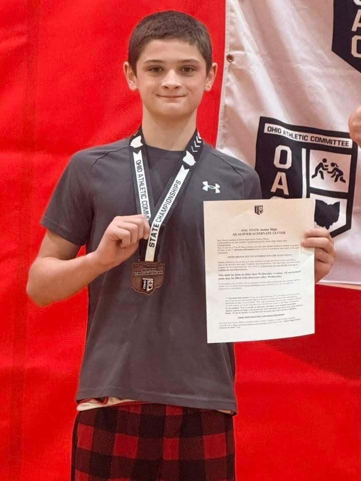 Nathan Beachy holding his medal and state qualifier letter